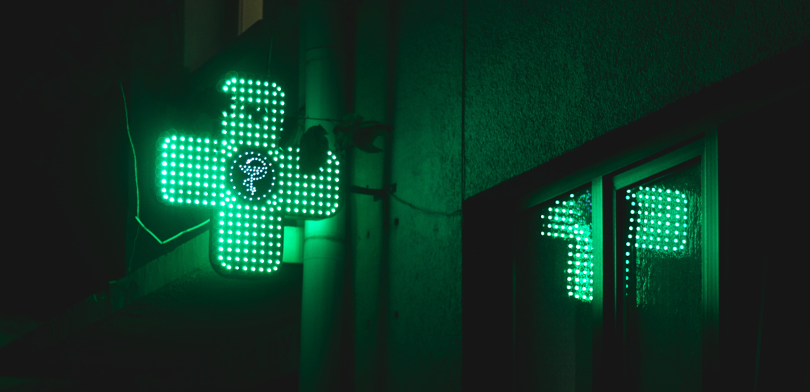 une croix de pharmacie allumée dans la nuit